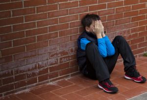 bambino disperato si copre il volto