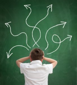 Confused schoolboy looking at arrows pointed in different directions,  back view,