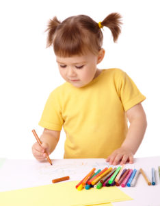 Cute child draws with color felt-tip pens, isolated over white