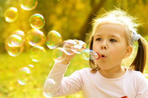 Cute little girl is blowing a soap bubbles